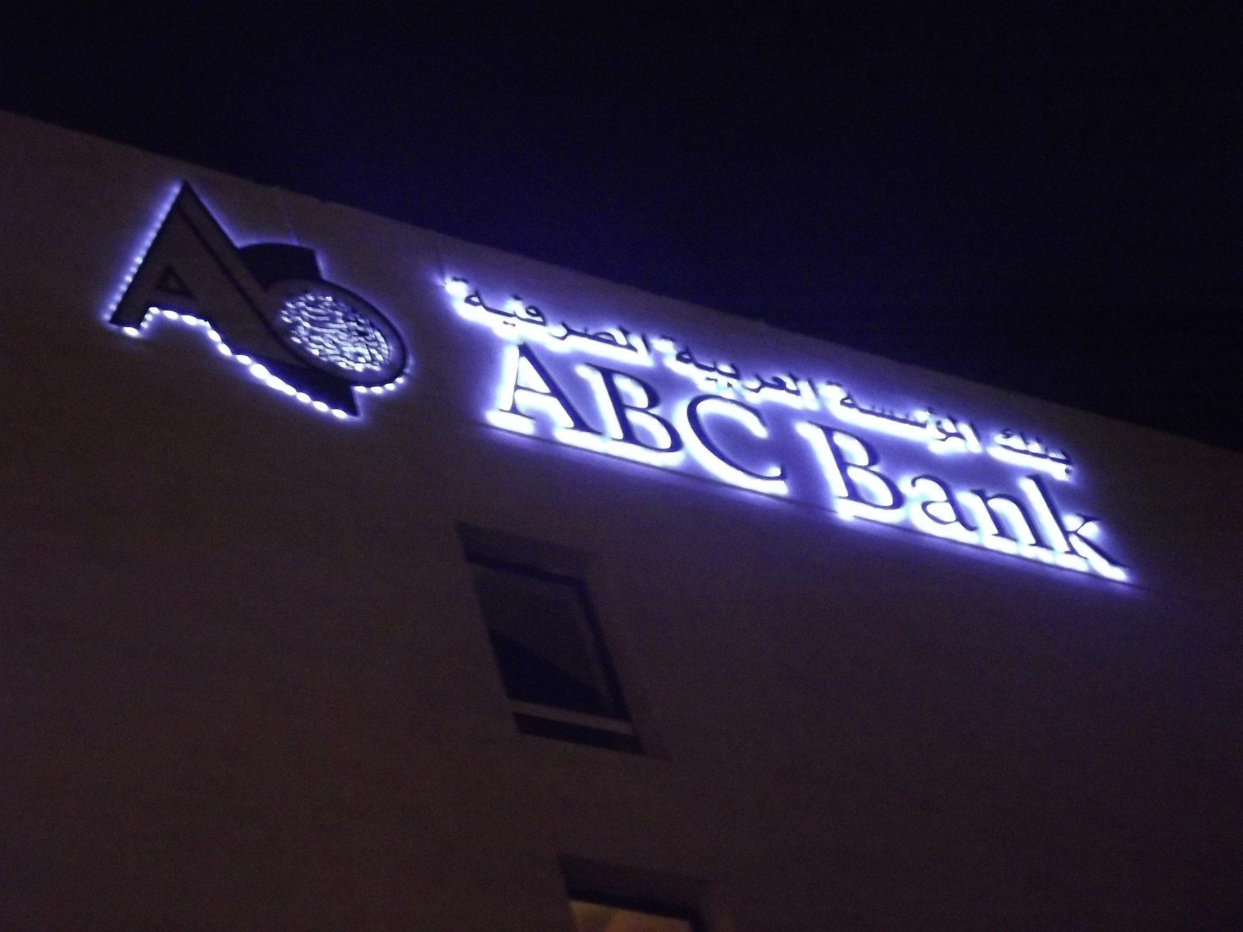 Illuminated channel letters and logo on a stone building facade at night.