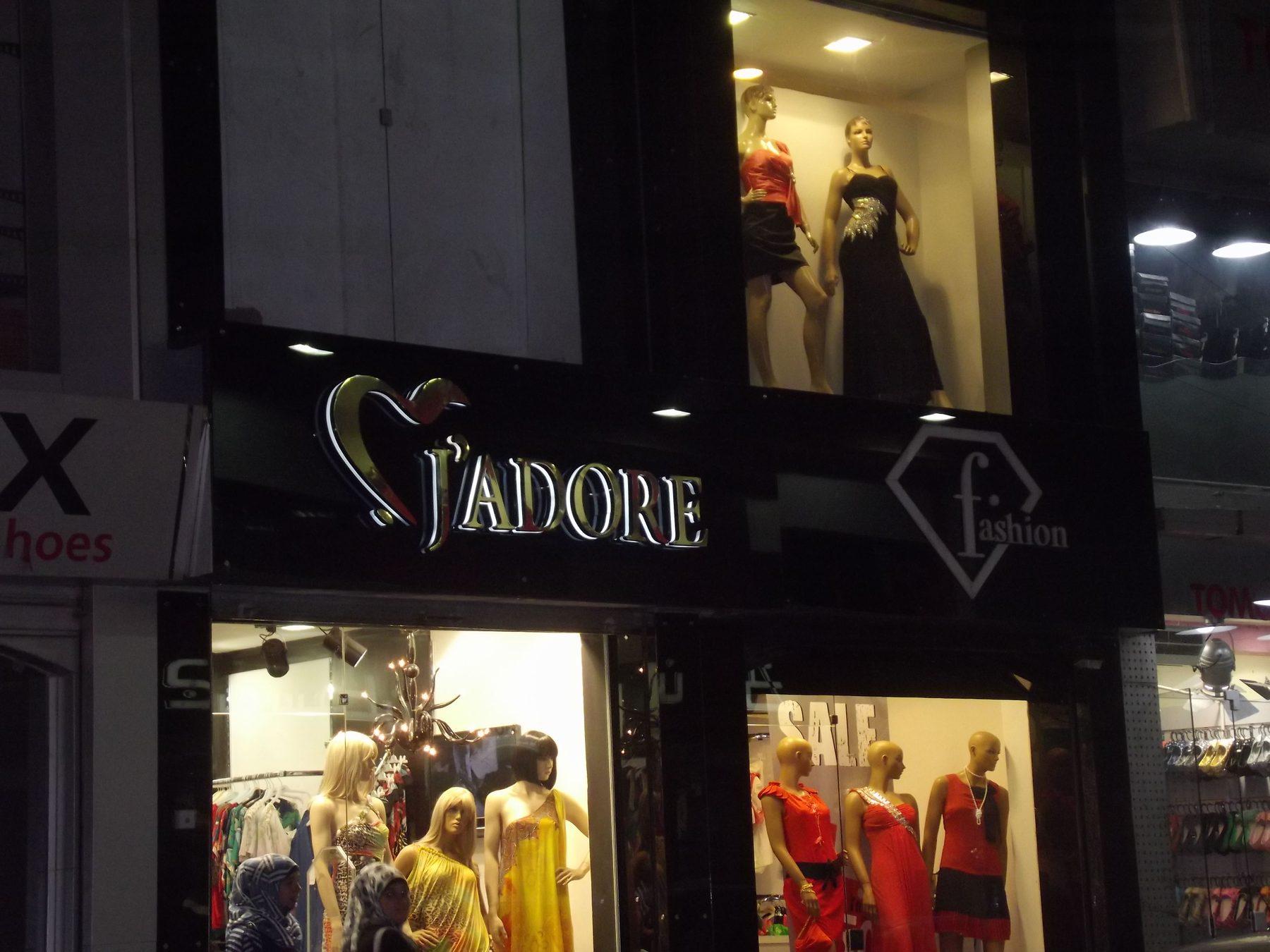 Illuminated fascia above lit boutique windows at night