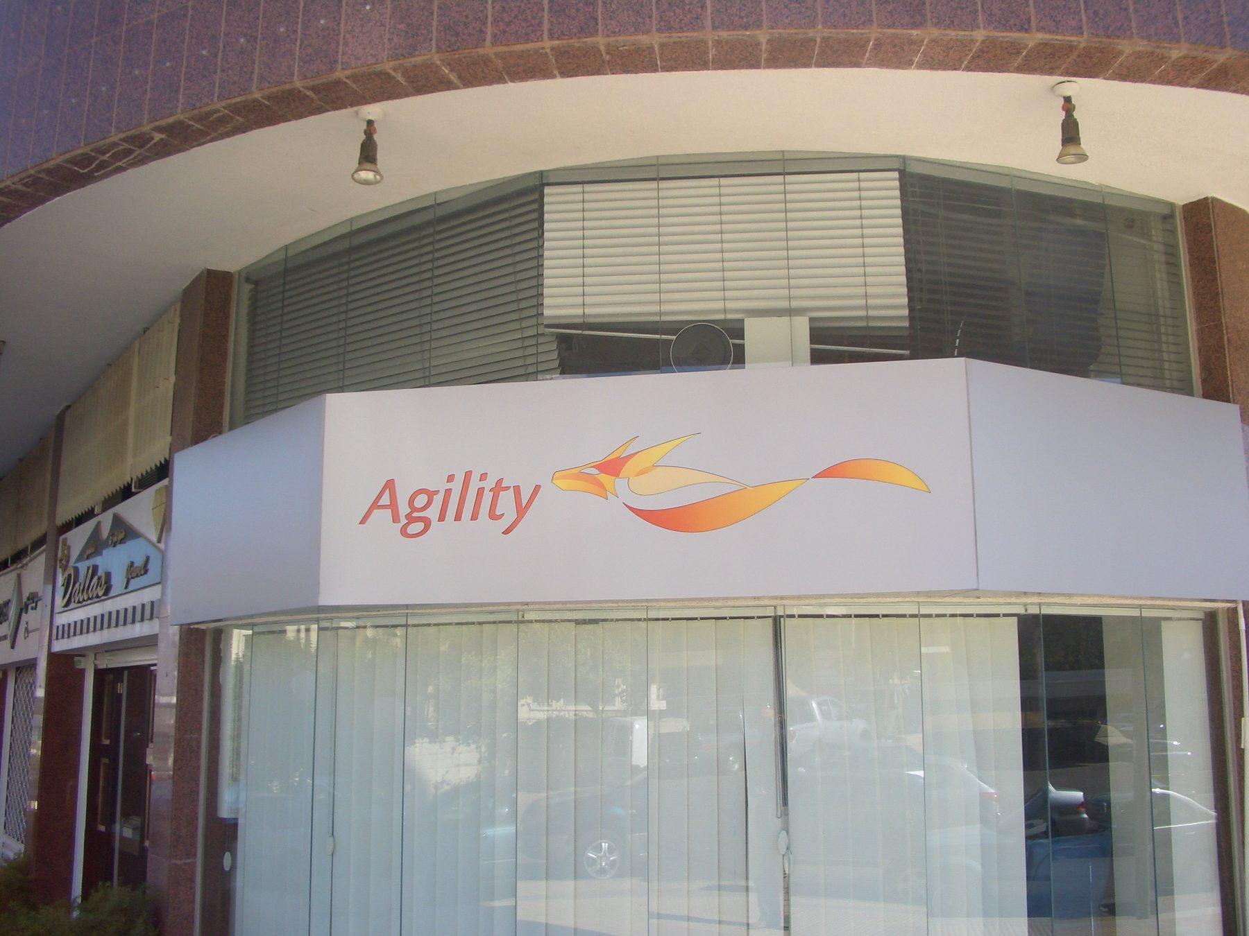Building entrance fascia with a white logo panel above the glass doors