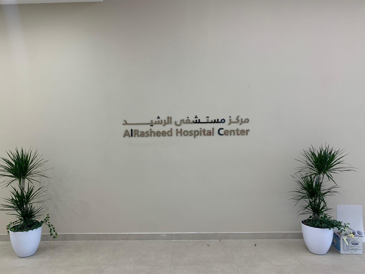 Raised lettering on a plain white wall beside potted plants