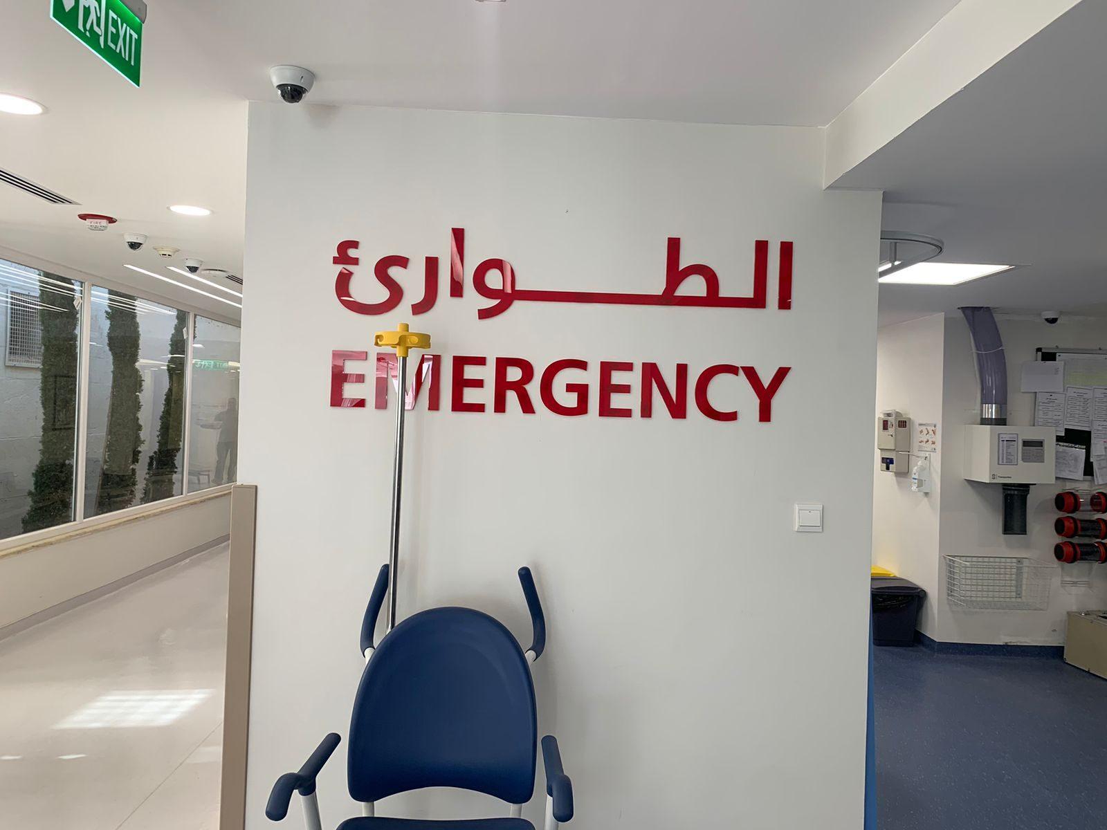 Red emergency lettering in Arabic and English on a white wall