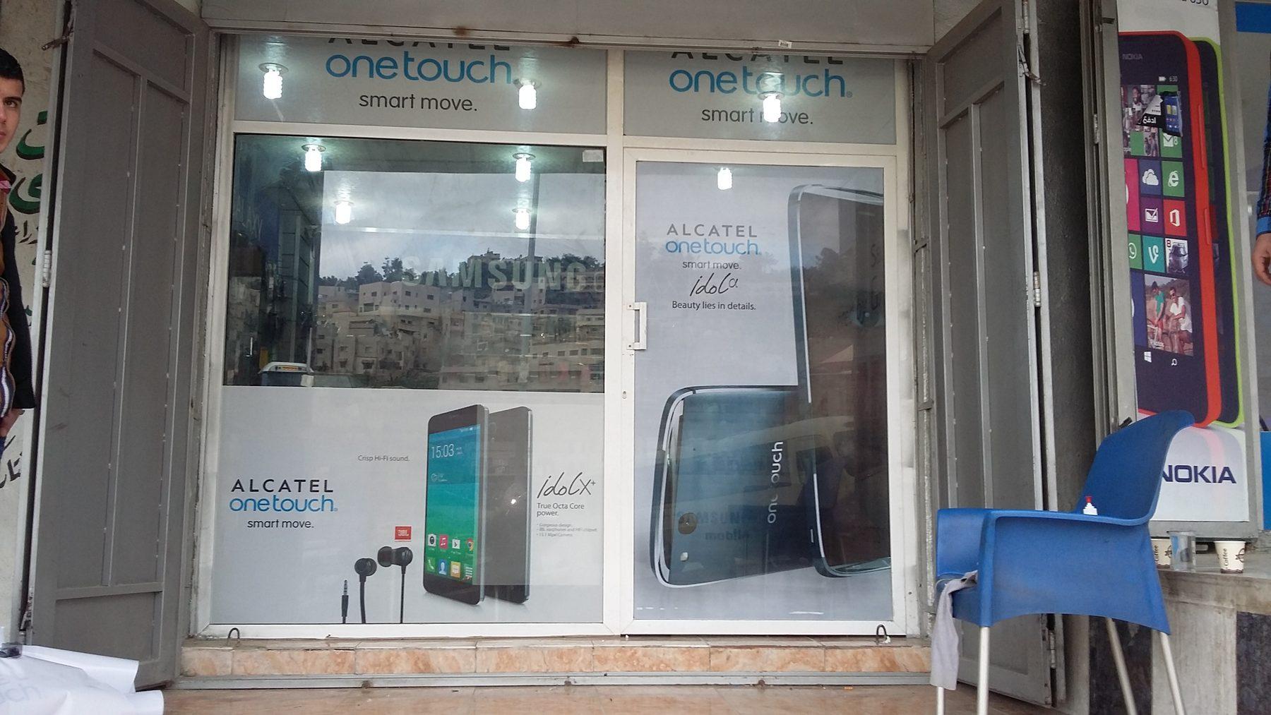 Window graphics on a shop front with another brand sign beside it