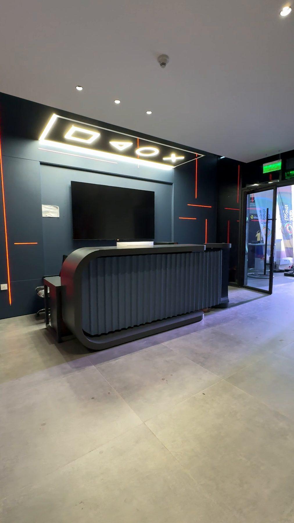 Reception desk with a lit game-controller graphic above it.