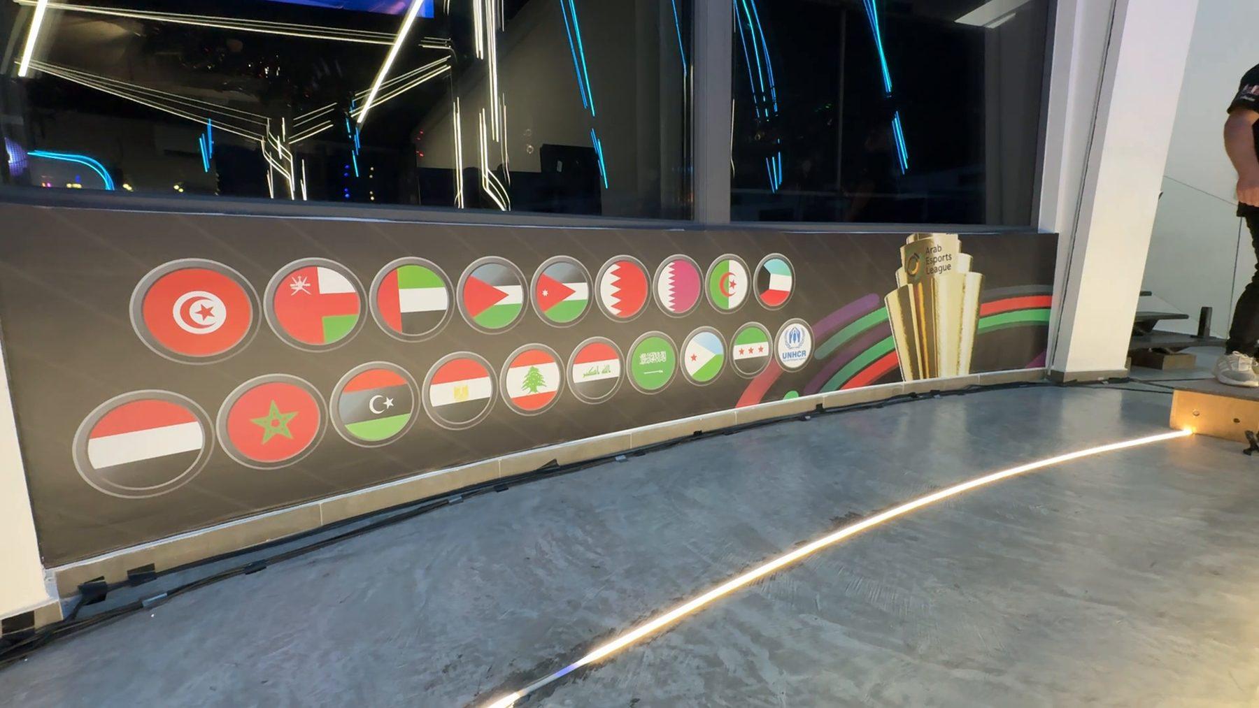 A curved wall of the participating nations' flags beside the stage.