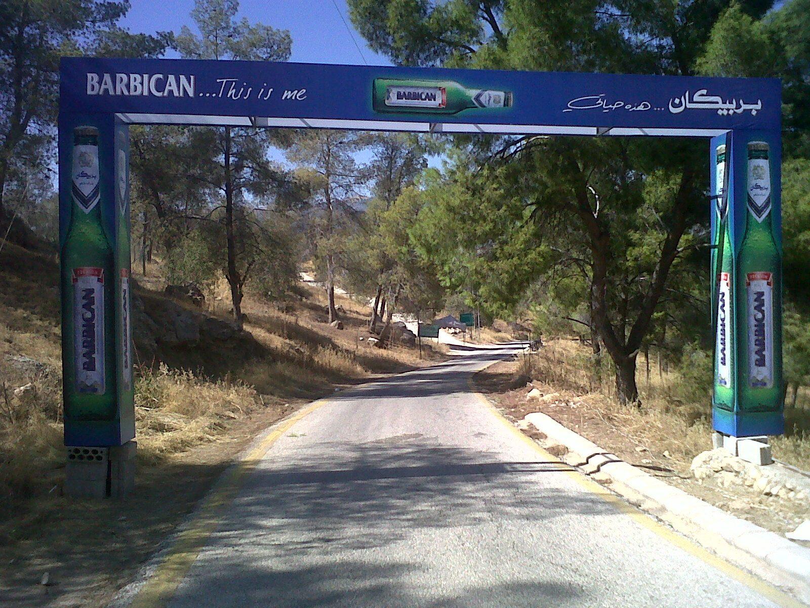 Blue arch with bottle graphics and brand name over the road
