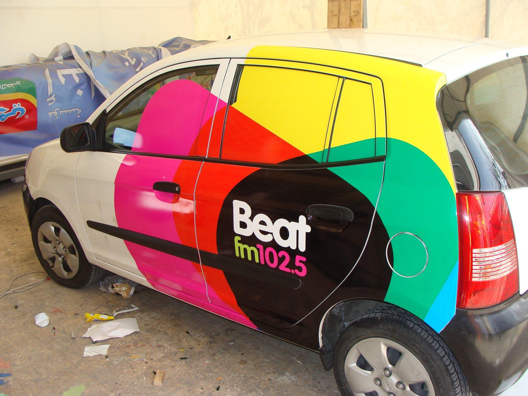 Rear three-quarter of the car with a bold multicolour side graphic and logo