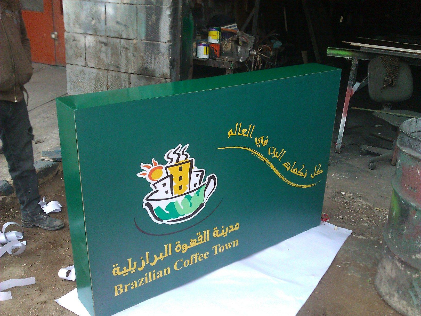 Green fabricated sign panel with logo and Arabic text in the workshop