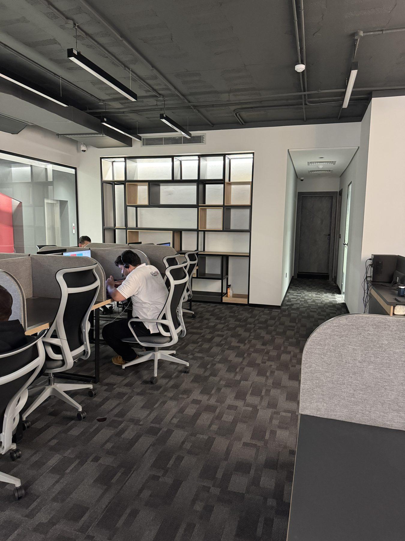 The open-plan office with the shelving wall behind.
