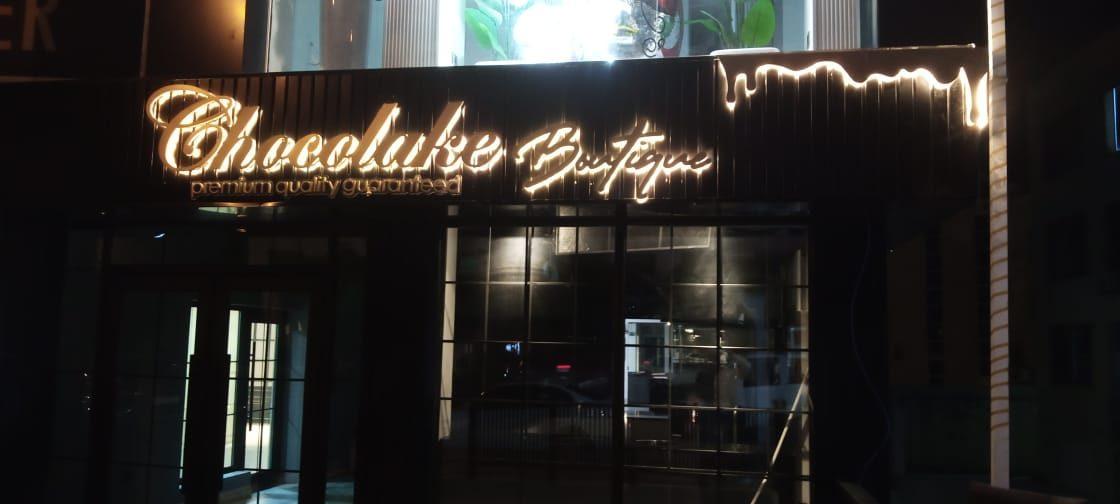 Illuminated script sign on a dark awning at night