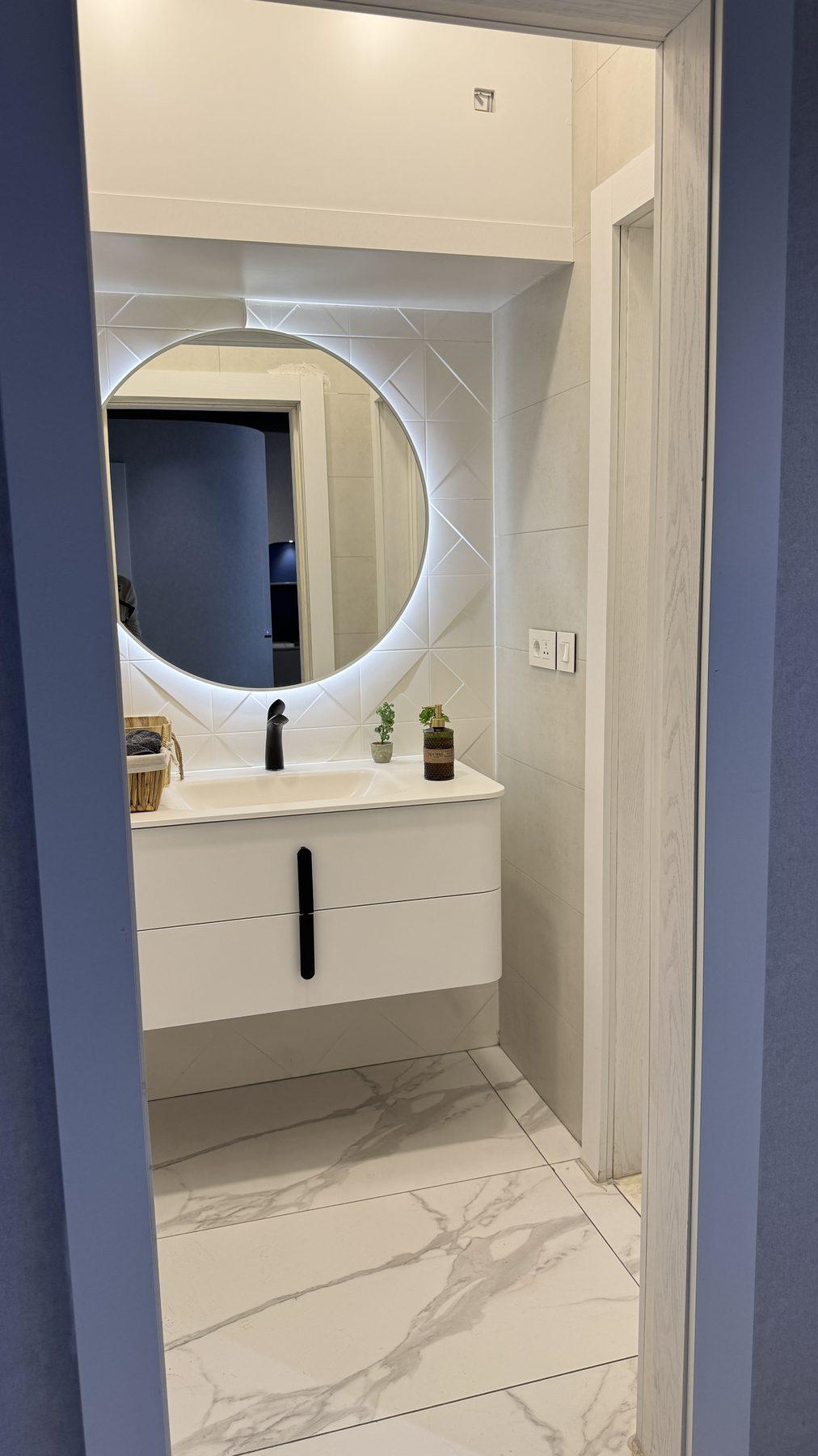 The washroom with a round lit mirror.