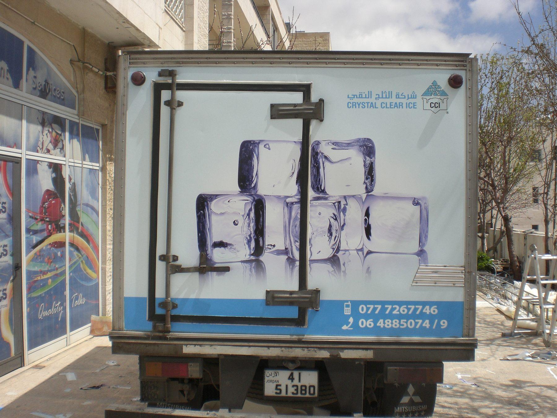 Rear of a white box truck with ice-cube artwork and the company logo.