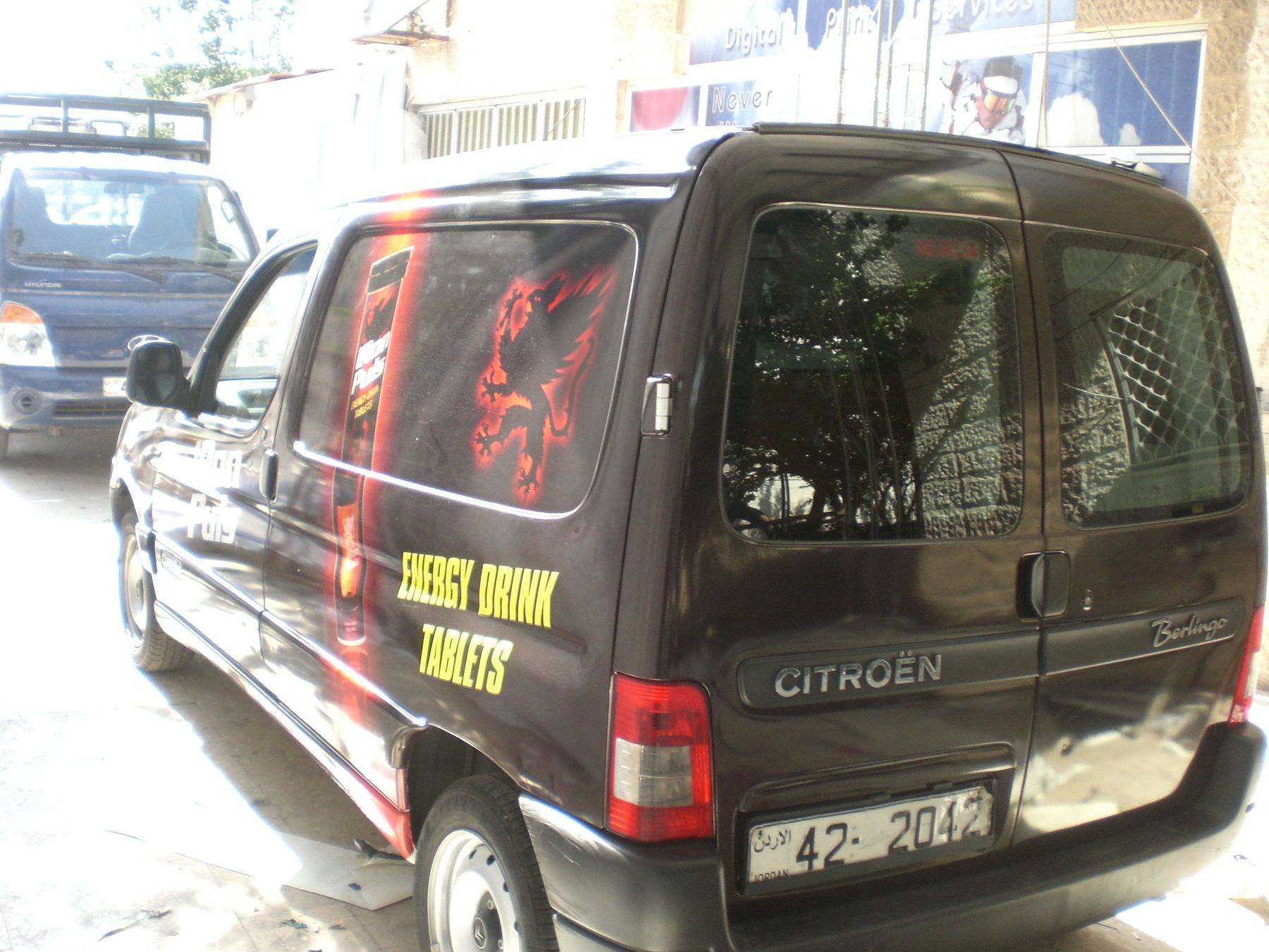 Rear three-quarter view of a dark van with red graphics