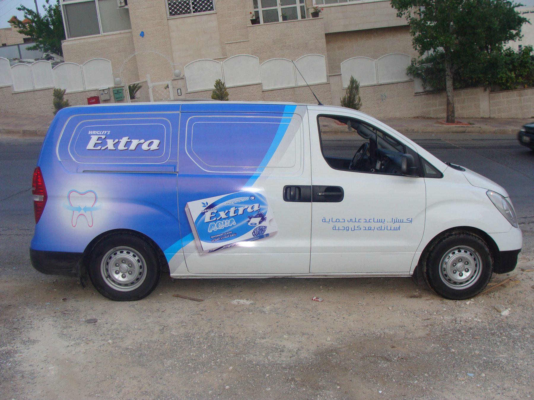 Side view of a white van with blue gradient graphics and a product pack panel.