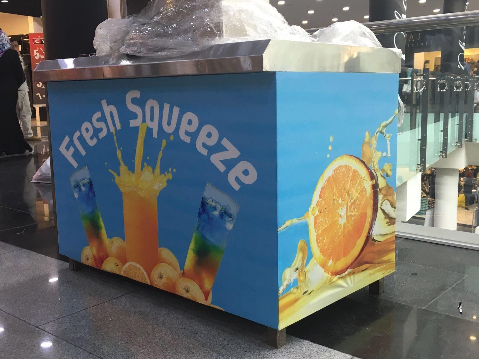 Juice kiosk wrapped in printed orange and blue graphics