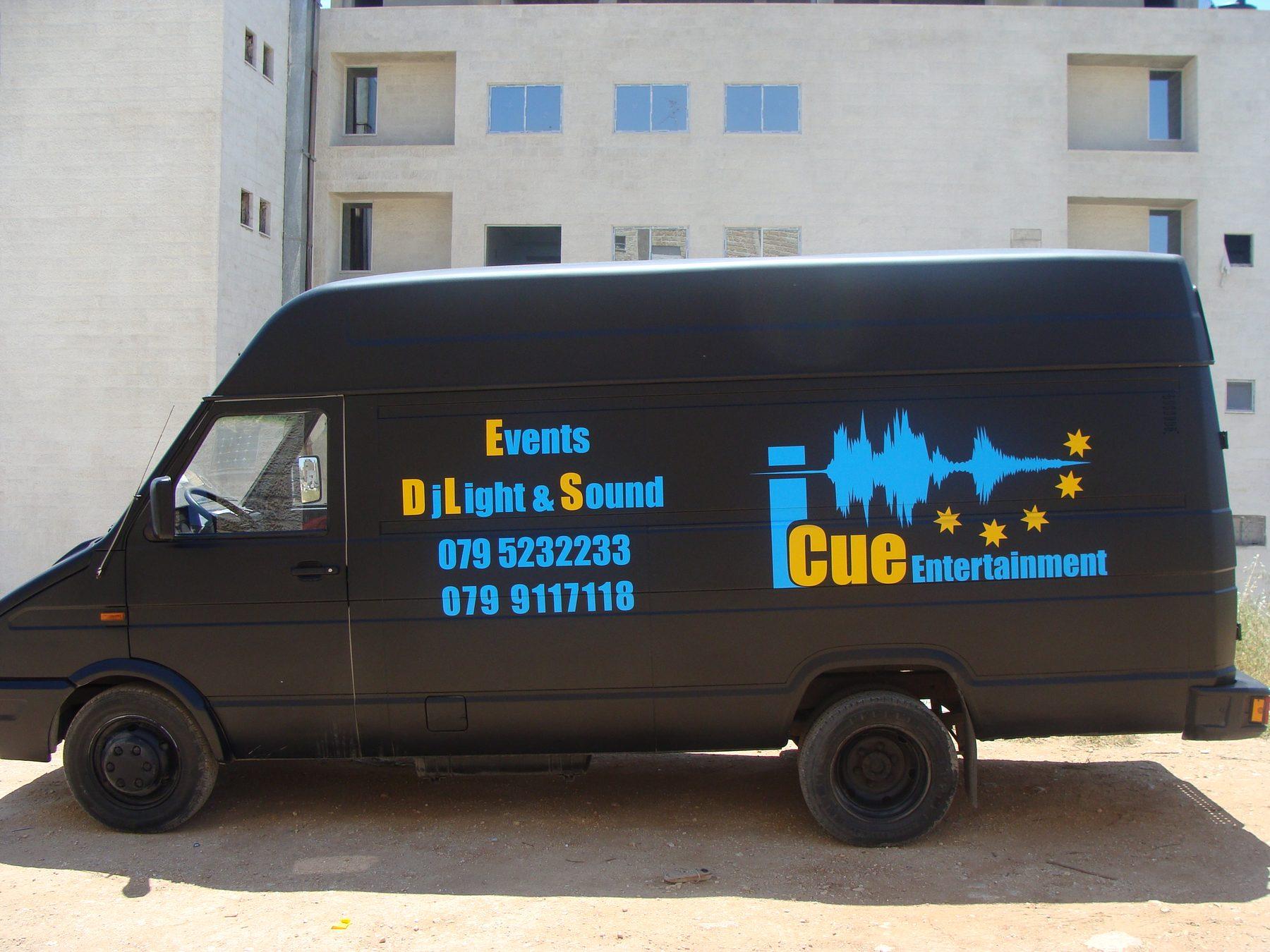 Side of a matt black high-roof van with lettering, a waveform logo and contact numbers.
