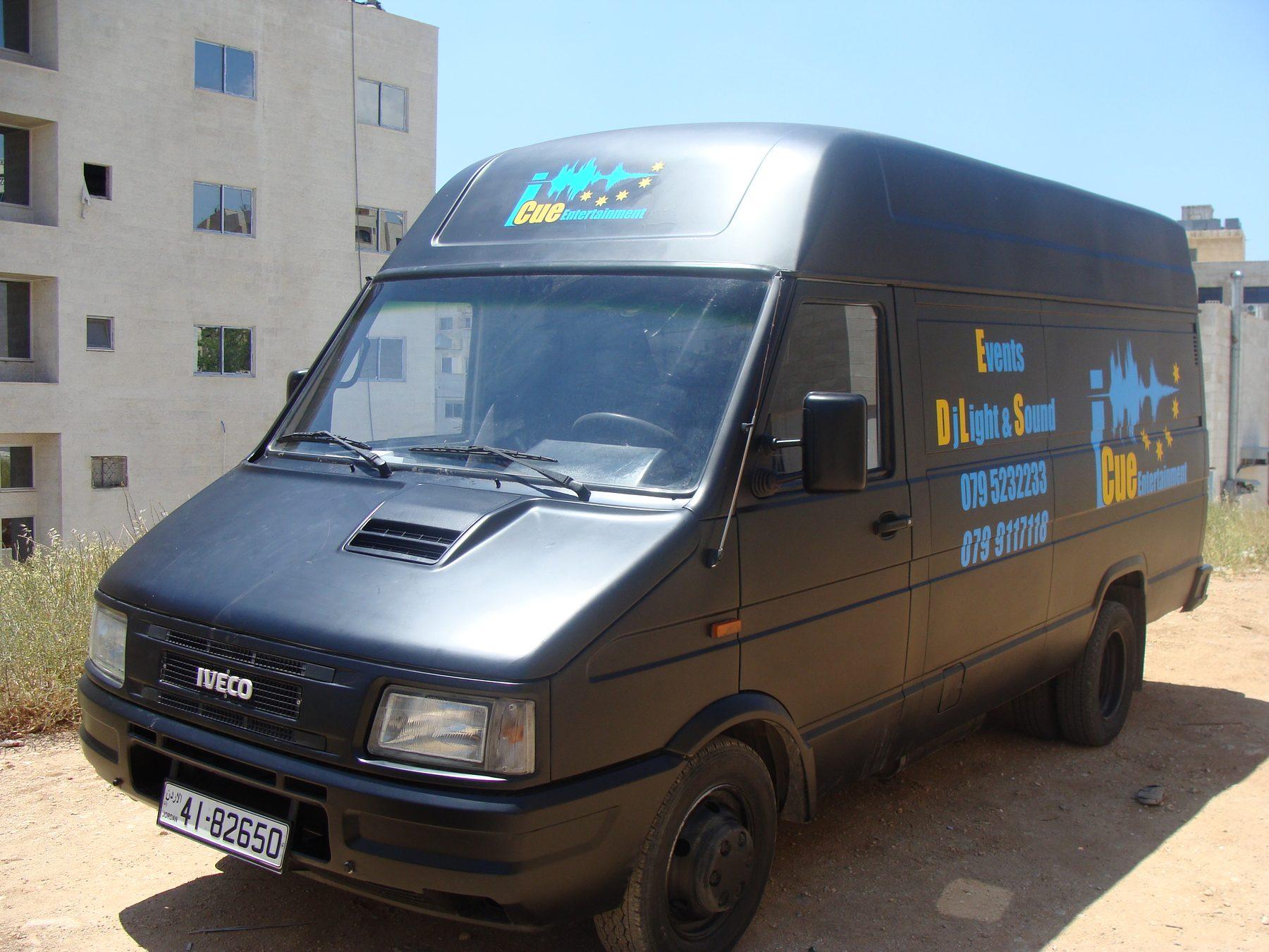 Front three-quarter view of the black van, with the waveform logo on its roof and side.