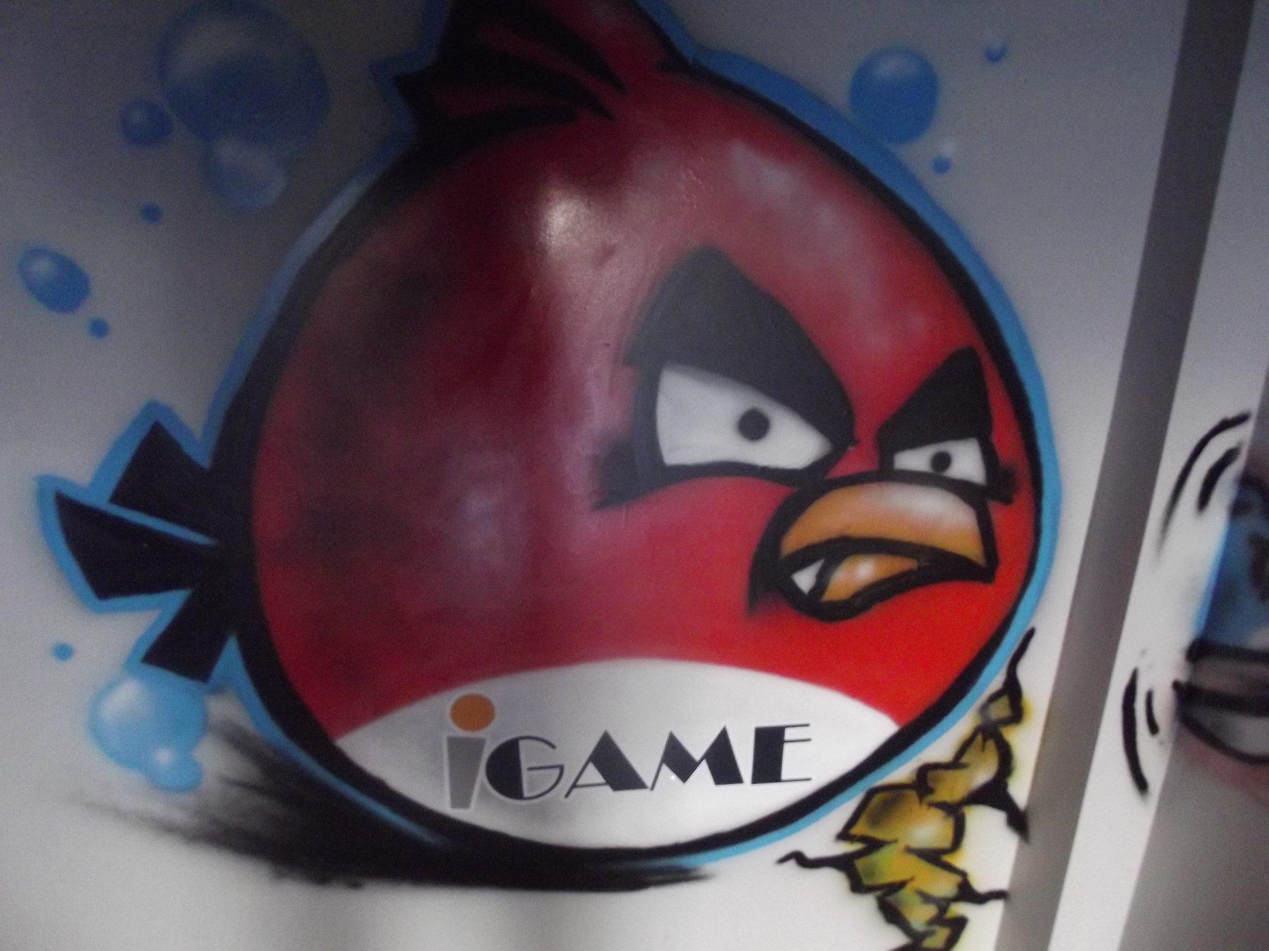 Airbrushed red cartoon bird character with logo on a white wall