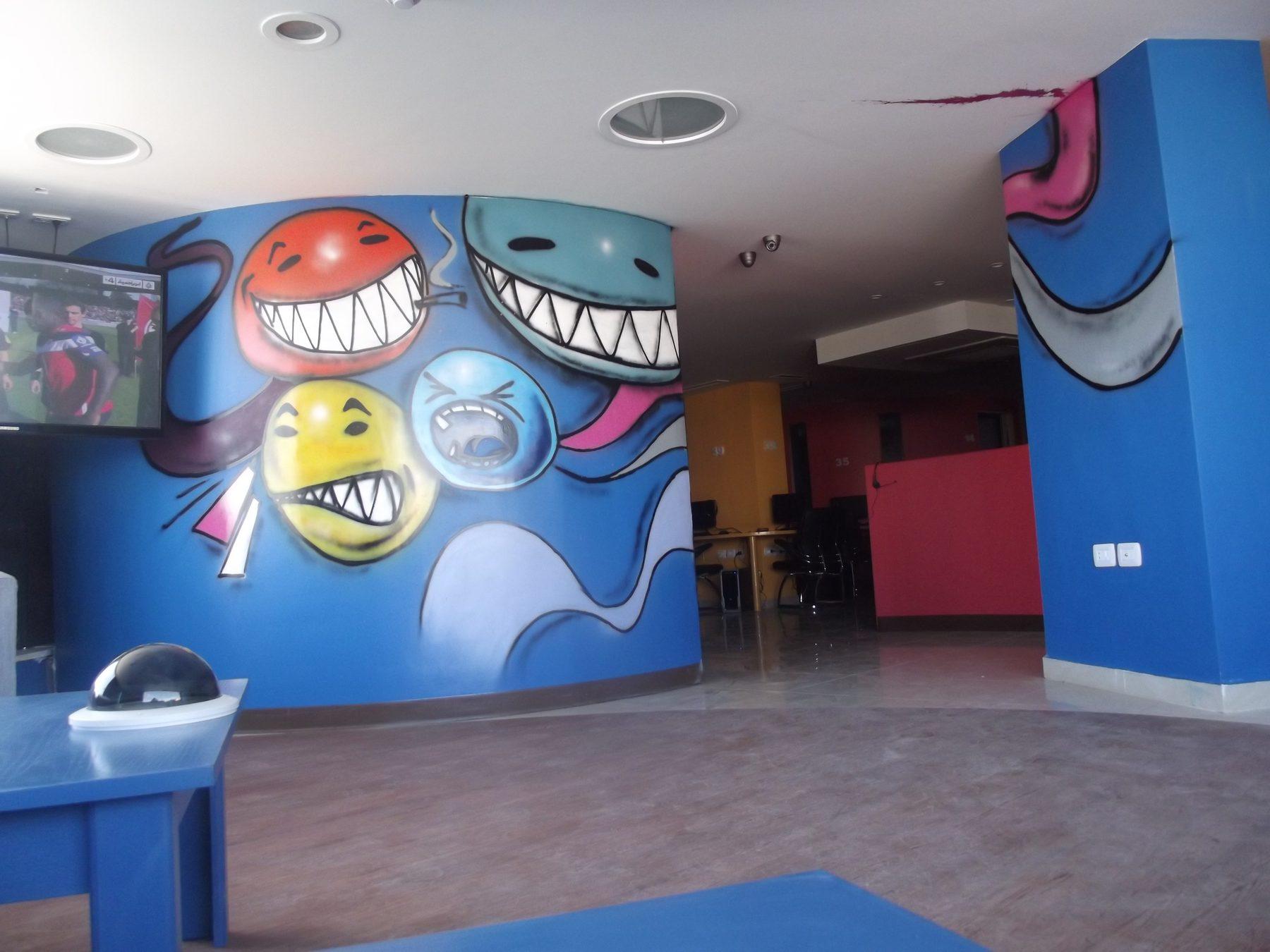 Blue interior wall with large cartoon face murals above a red counter area