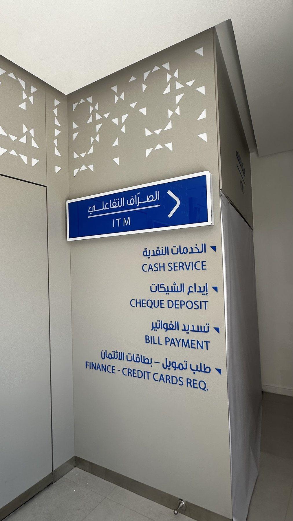 Illuminated wayfinding sign listing service points beside a perforated wall panel.