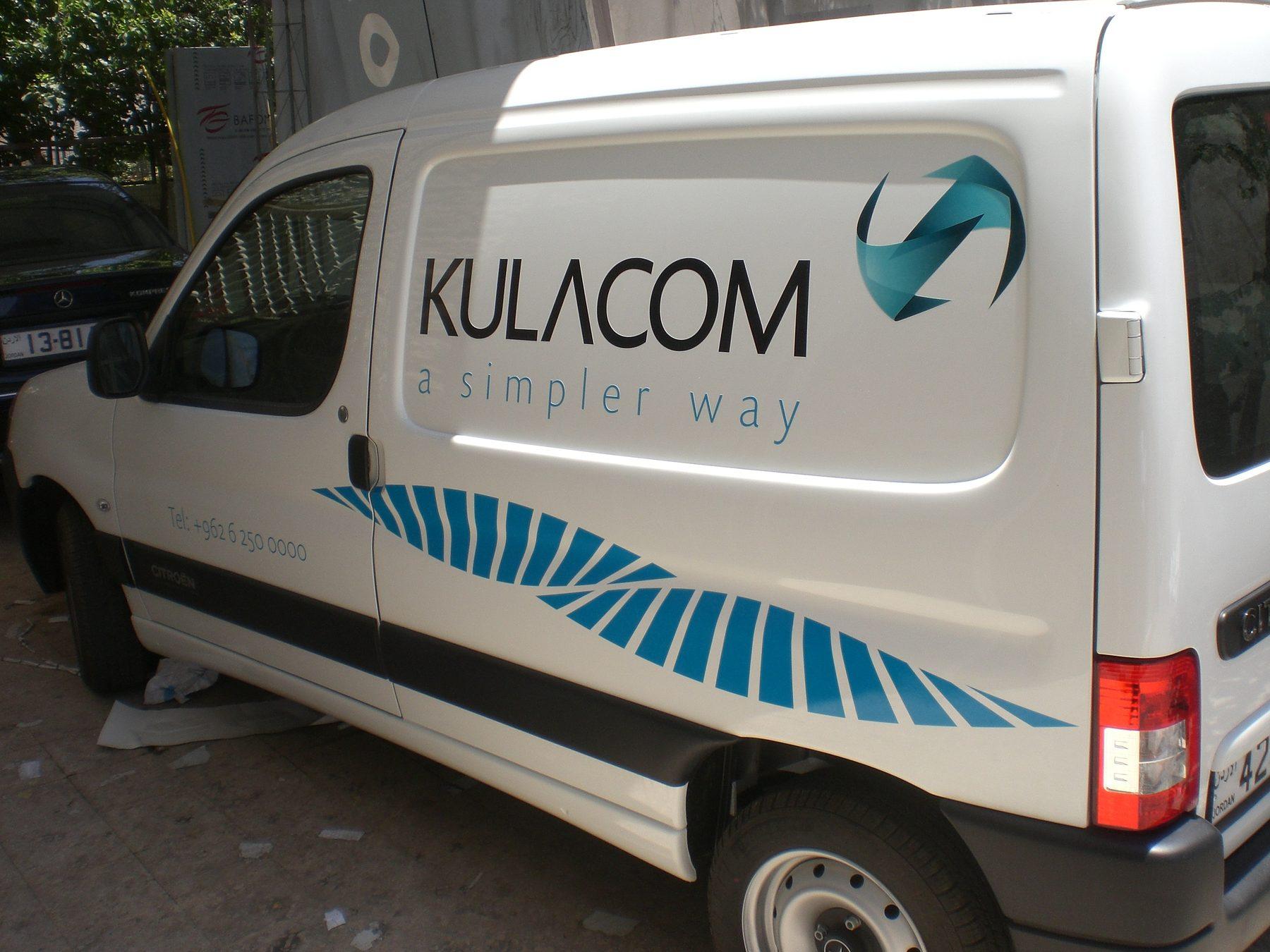Side three-quarter view of a white van with logo and wave stripe