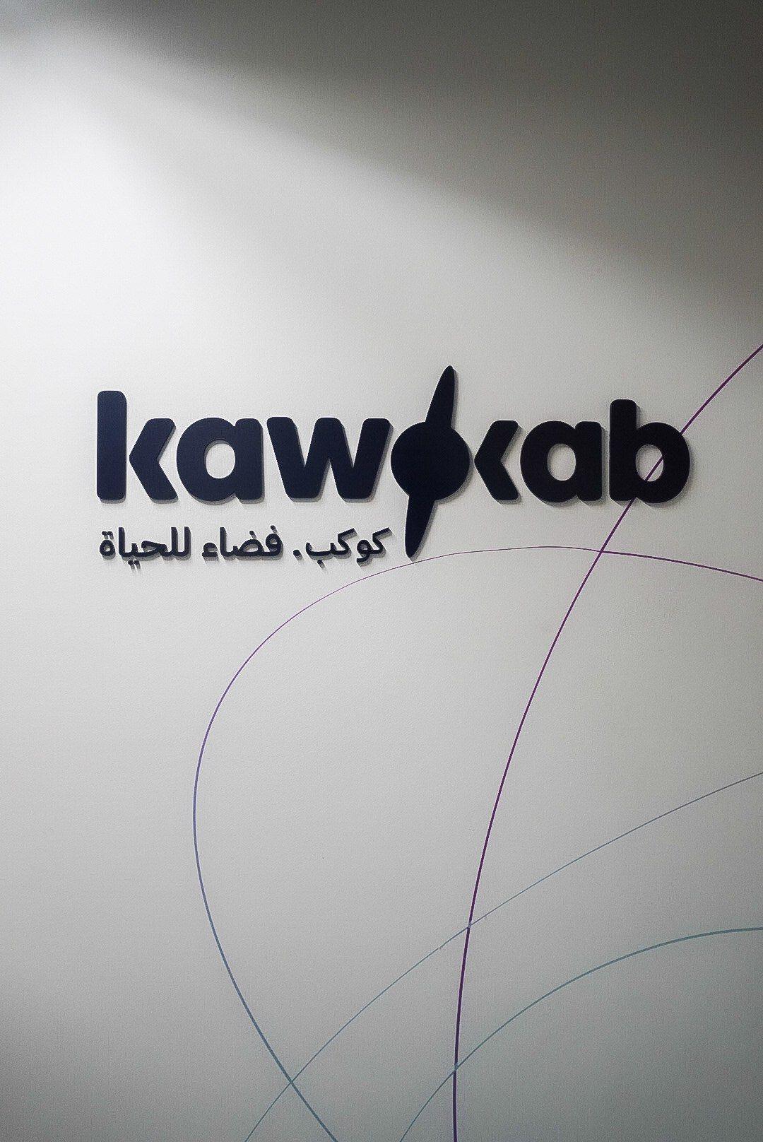 Dimensional logo letters with a swoosh mounted on a light grey wall.