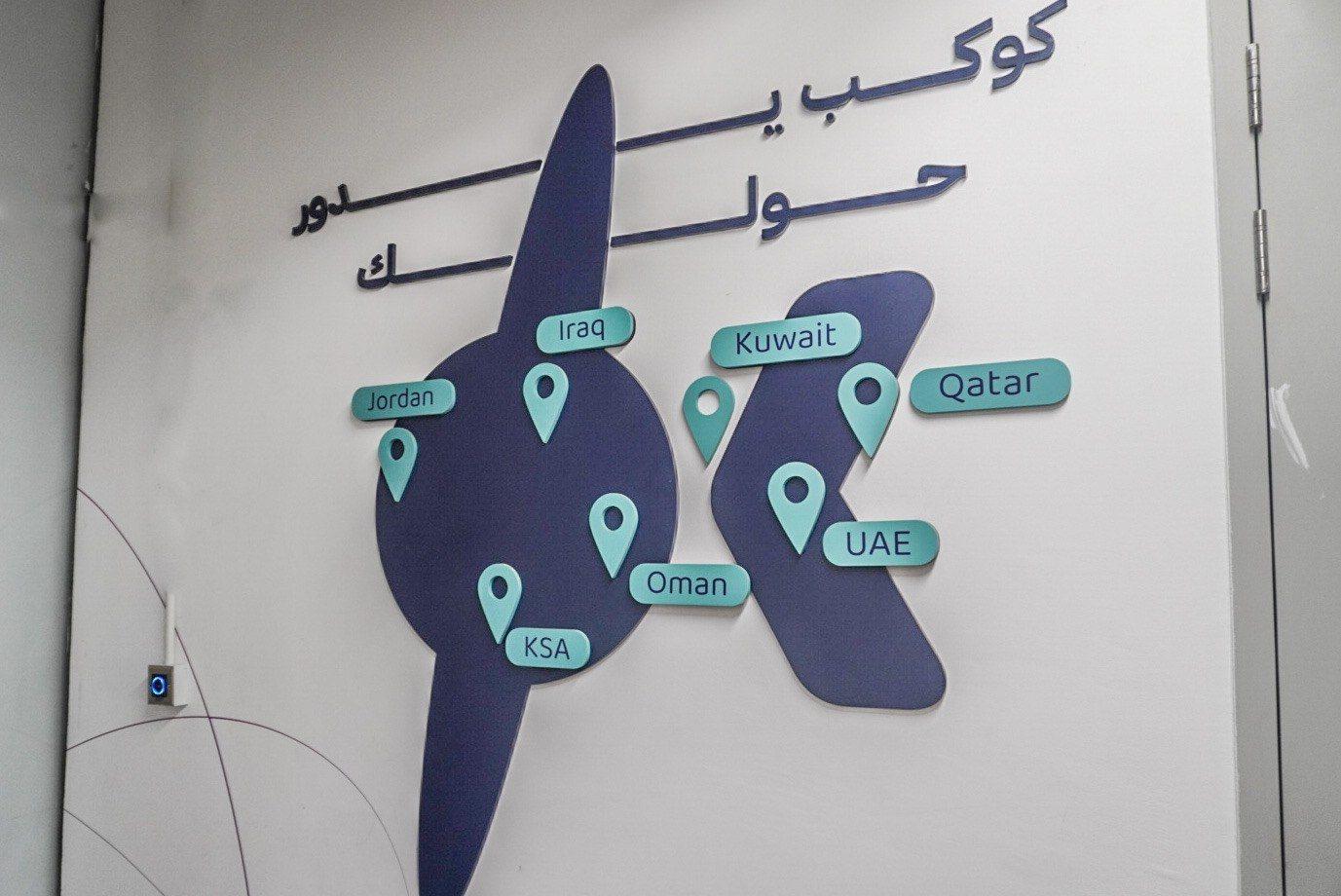 A dimensional logo with country pins mounted on a white wall.