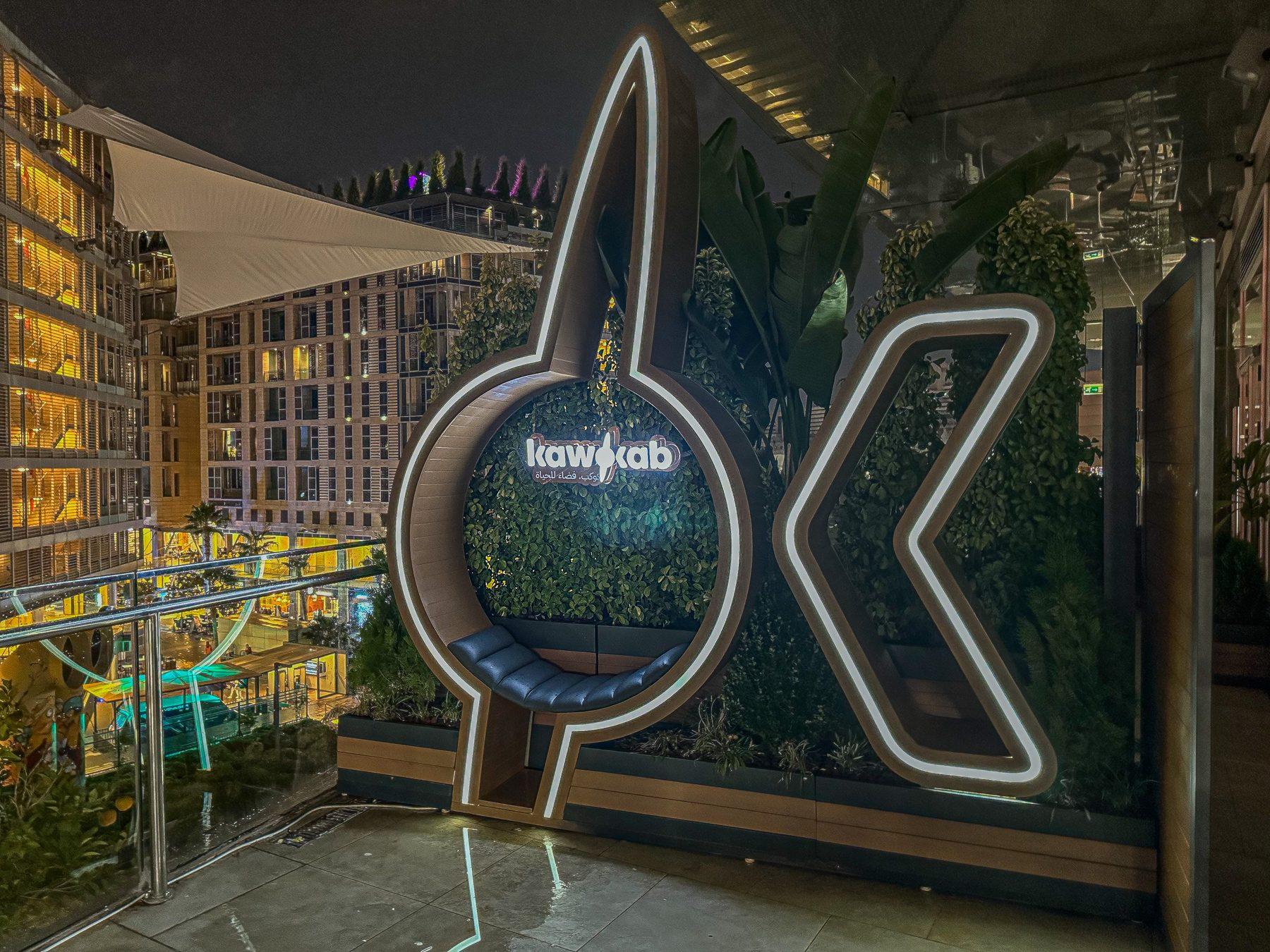 Illuminated ring-and-chevron logo on a terrace at night