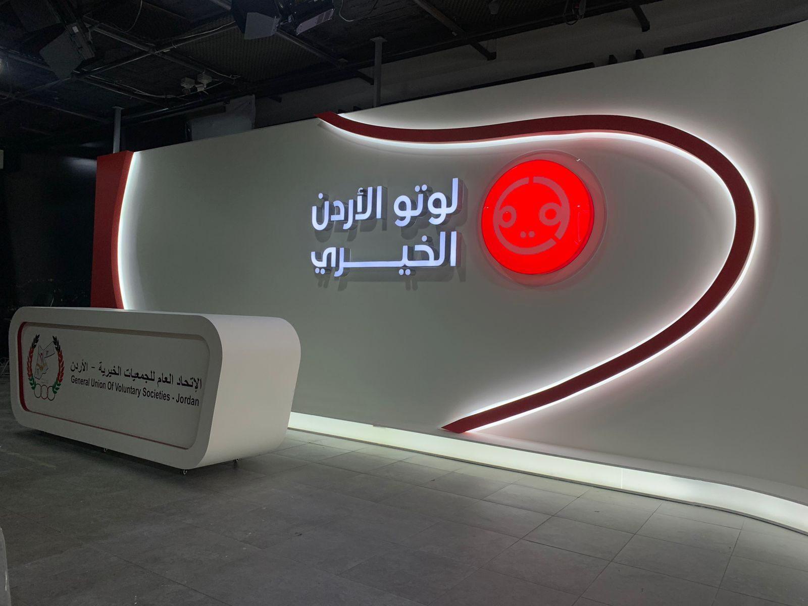 Studio set with an illuminated Arabic logo wall and a curved white desk