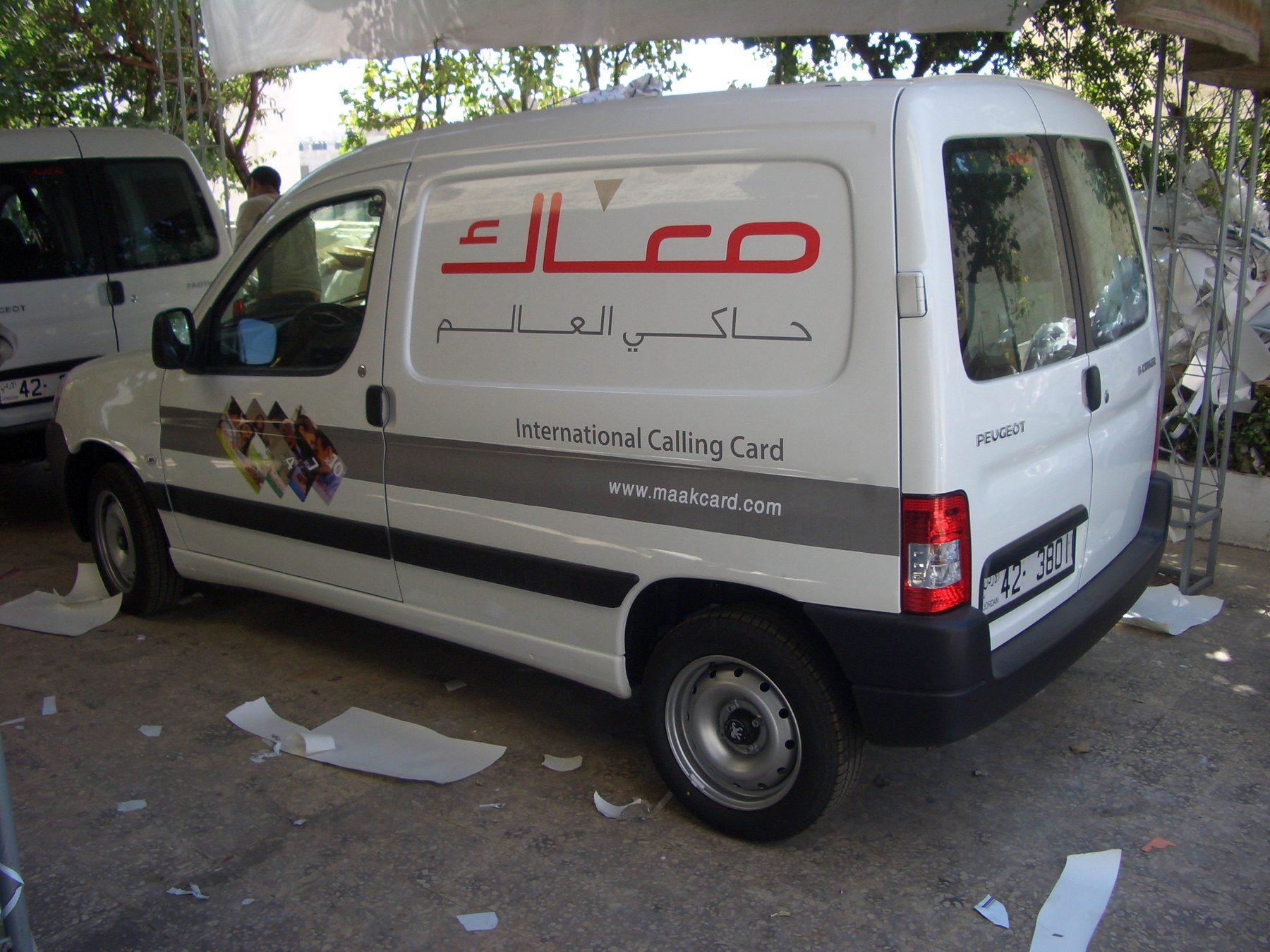Rear three-quarter view of a white van with calling card graphics