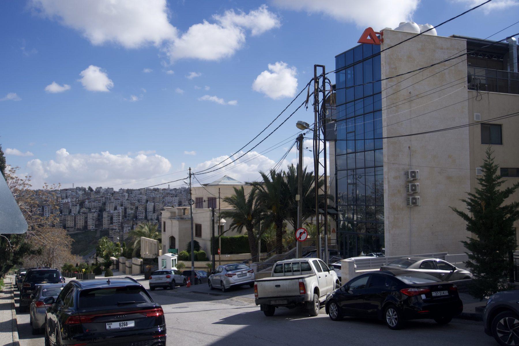 Red logo on a pylon in front of a glass building