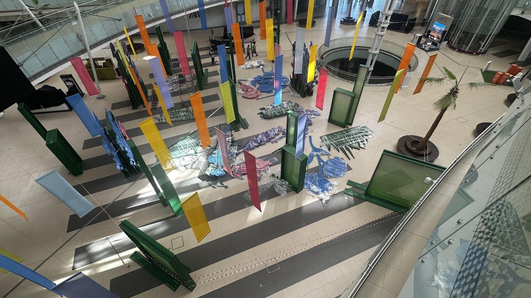 Overhead view of the atrium installation with colourful panels and a blue floor graphic.