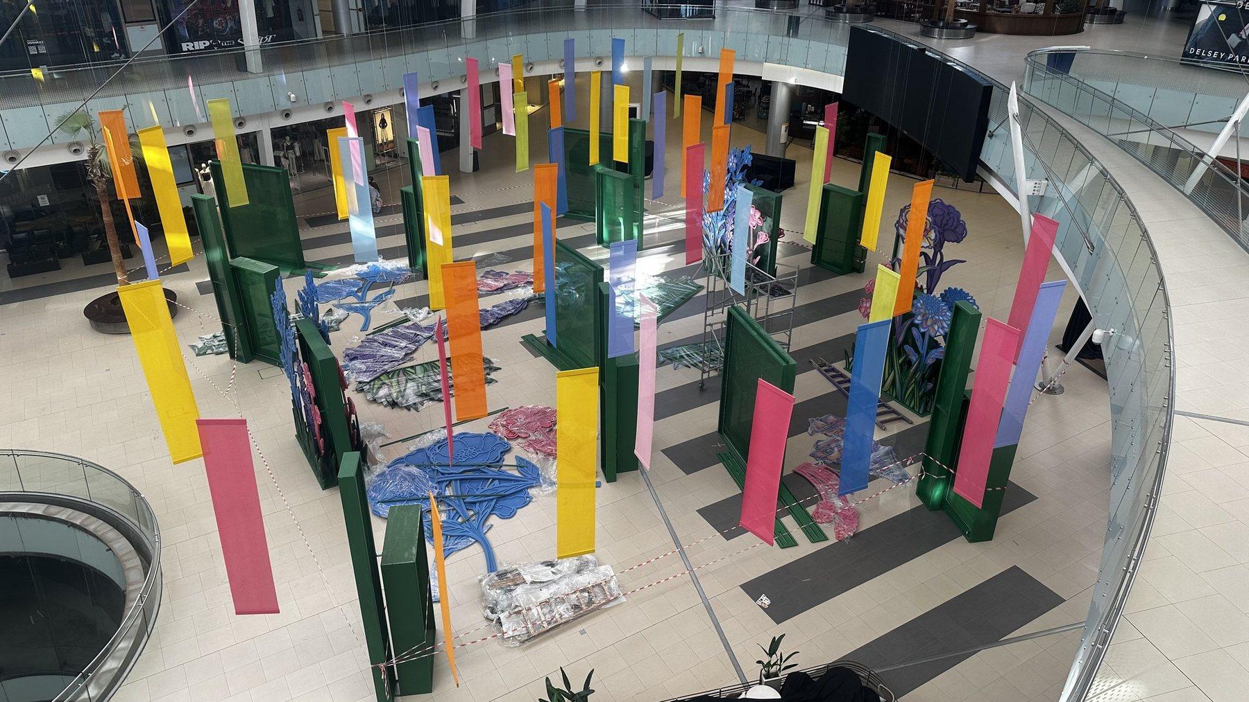 Elevated view of the atrium installation with colourful panels and a central blue display.