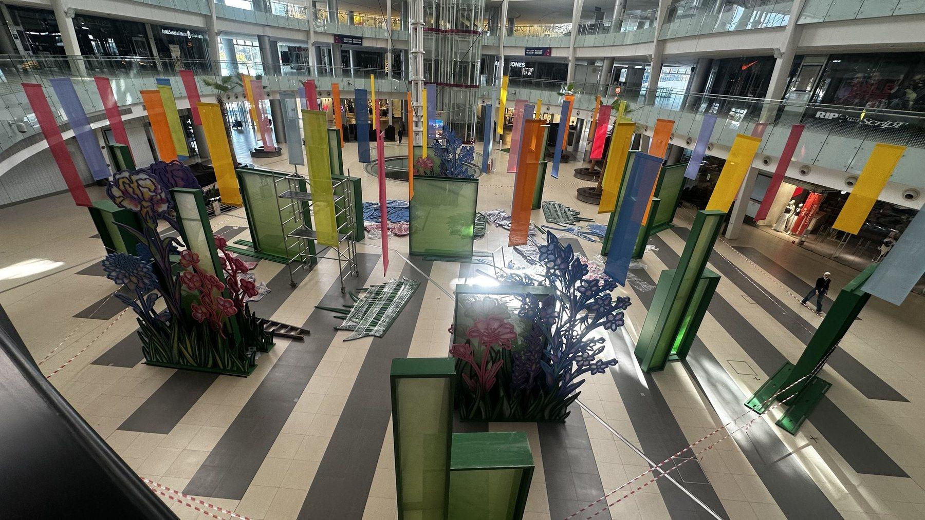 Atrium installation with green pillars and blue plant displays in daylight.
