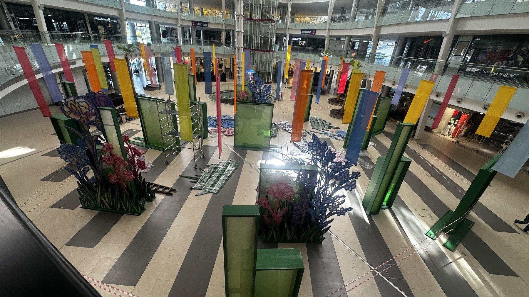 Atrium installation with coloured panels and blue floral displays on the floor.