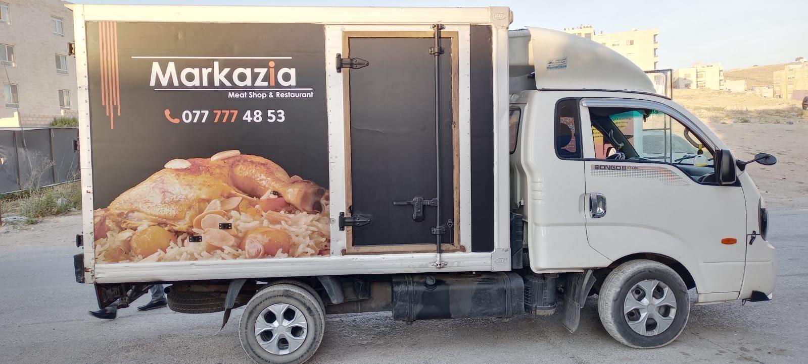 Box truck with a chicken dish image, logo and phone number on its side panel.