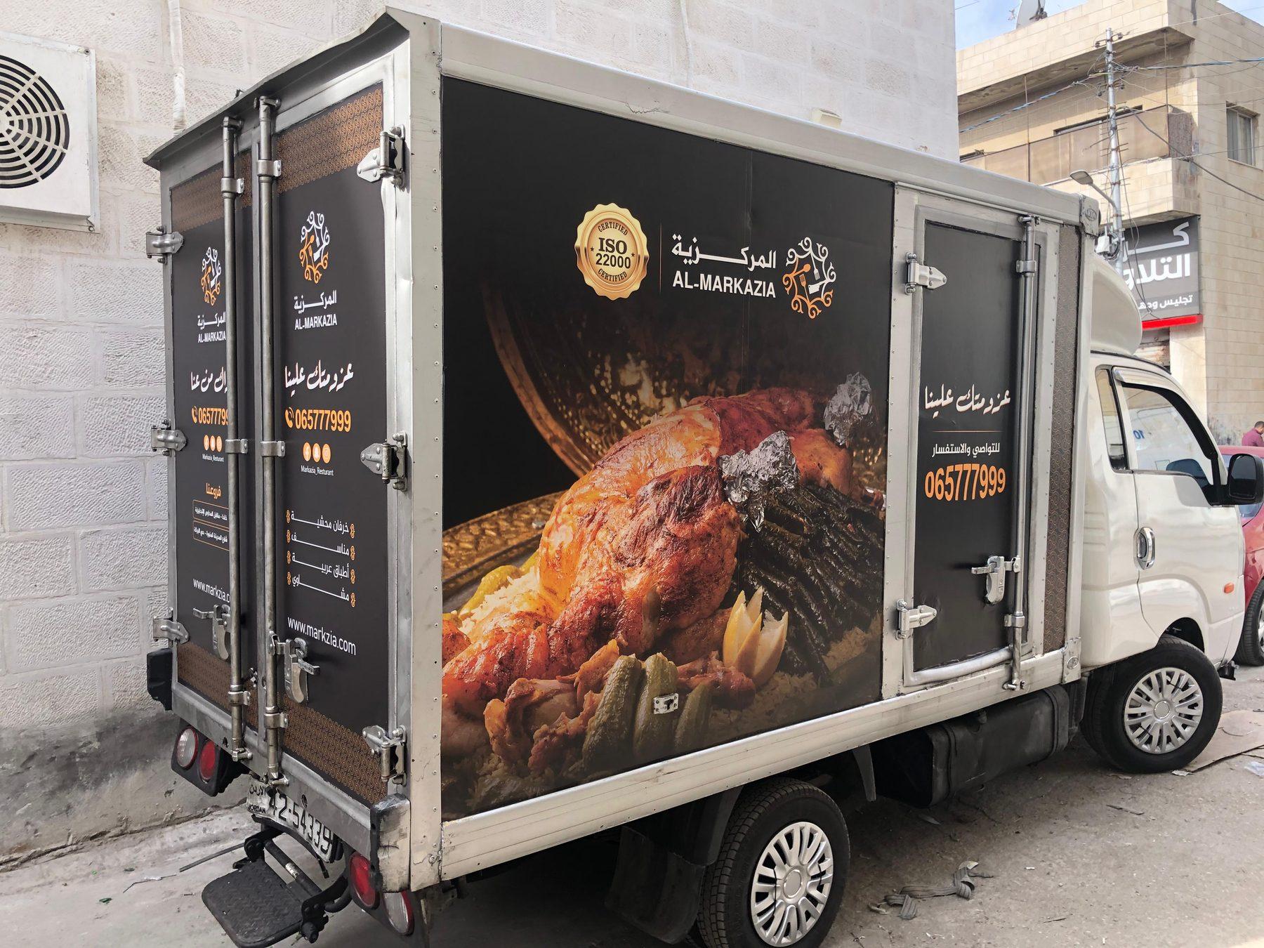 Box truck wrapped with a roasted chicken image and Arabic text on its side and rear.