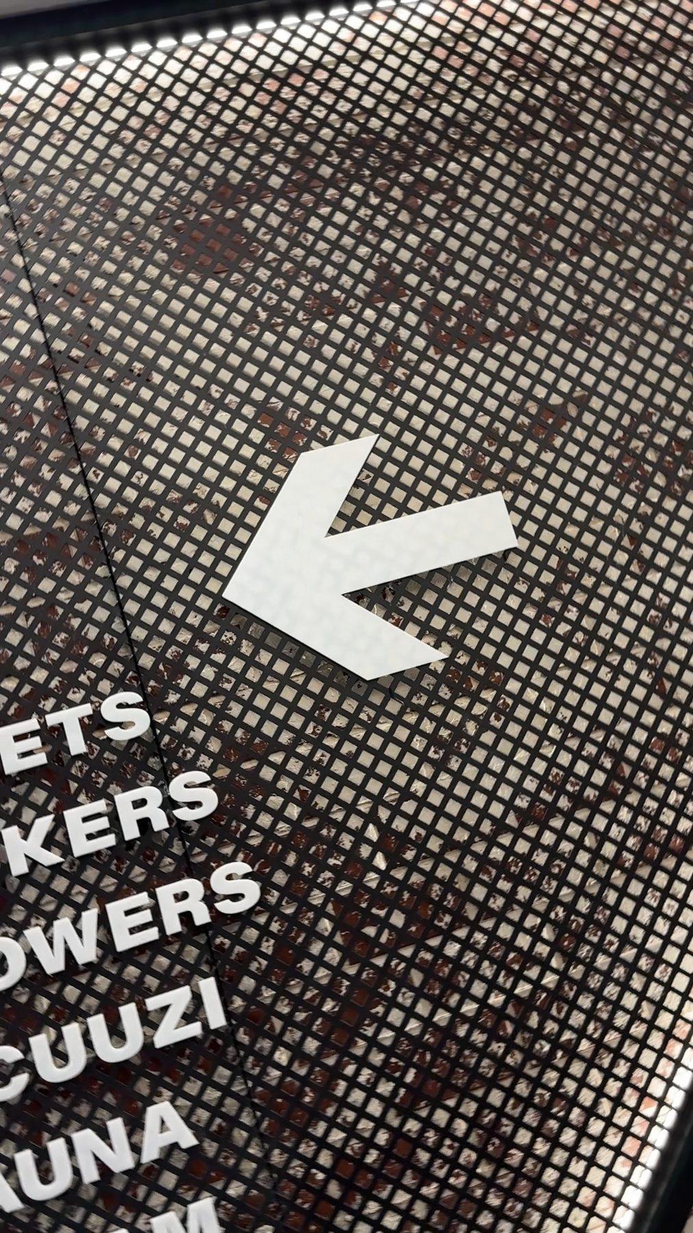 Perforated-metal wayfinding sign to the lockers, showers, jacuzzi and sauna.