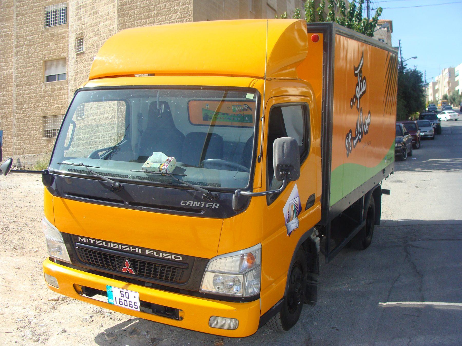 Yellow truck, front three-quarter view with box wrap in frame