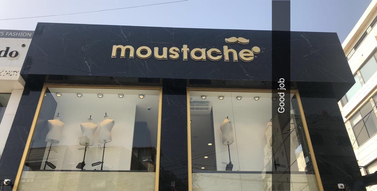 Black fascia with a gold-tone logo over a clothing shop front