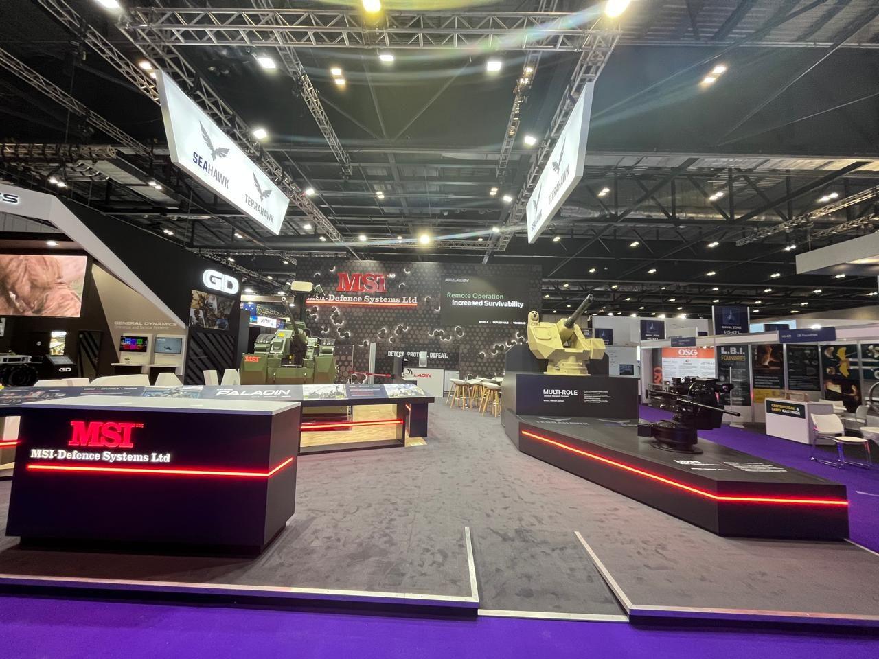 Wide view of the exhibition stand with vehicle displays and overhead signs