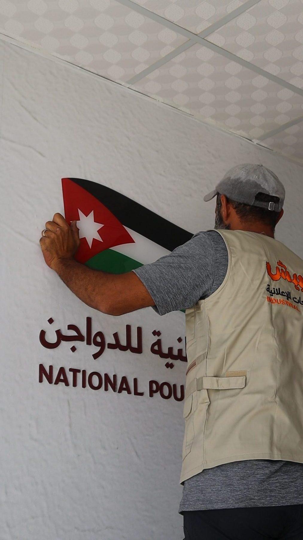 فنّي يثبّت العلم بجانب اسم الشركة.