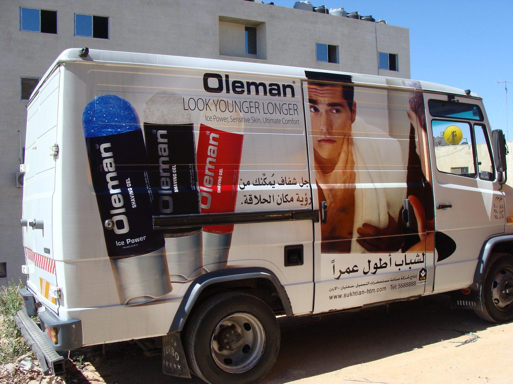White truck with a wrap showing a model and product packs on the box side.