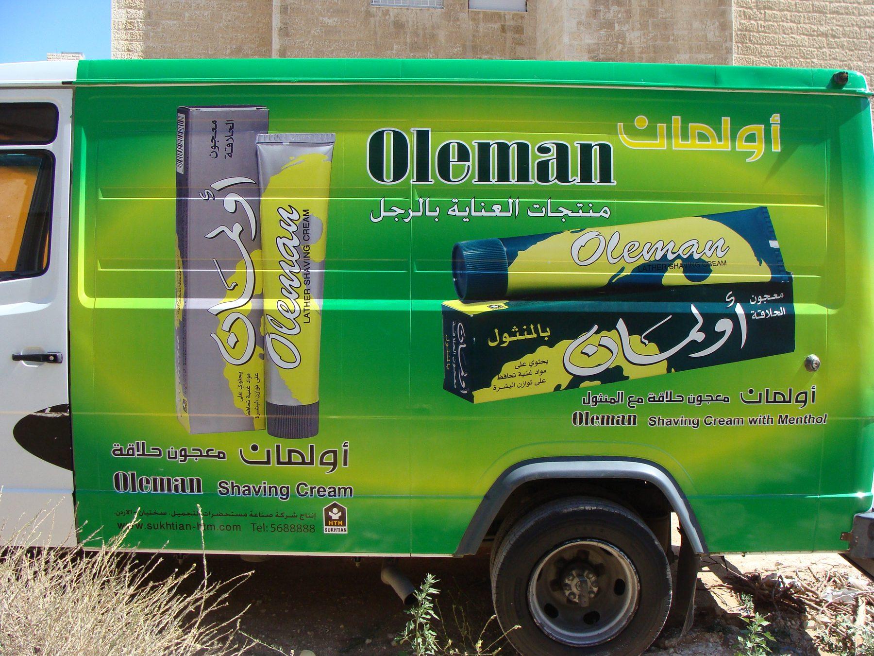 Green box truck side with product packs and Arabic and English lettering.