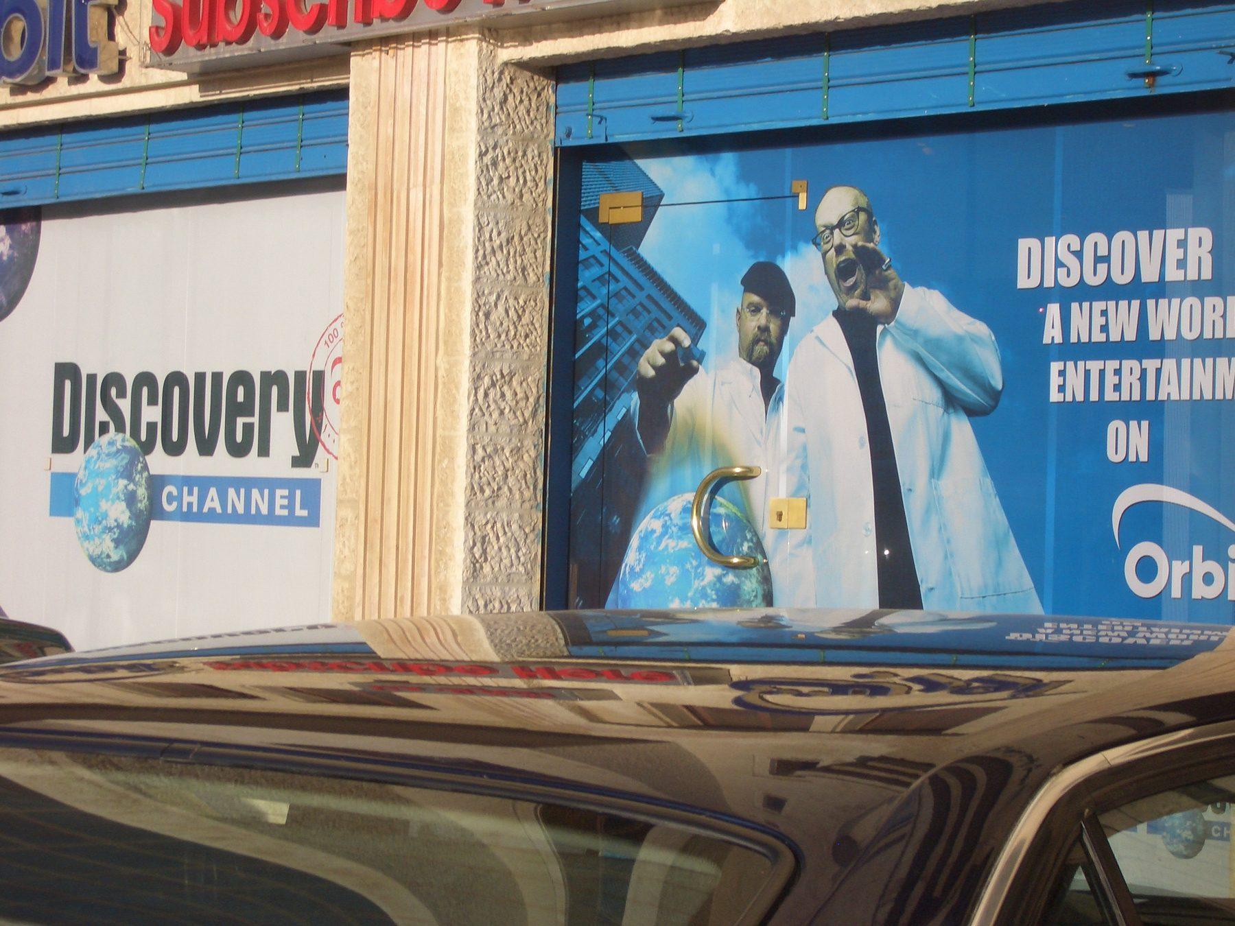 Printed billboard showing a man in a white coat with the slogan 'Discover a new world'.