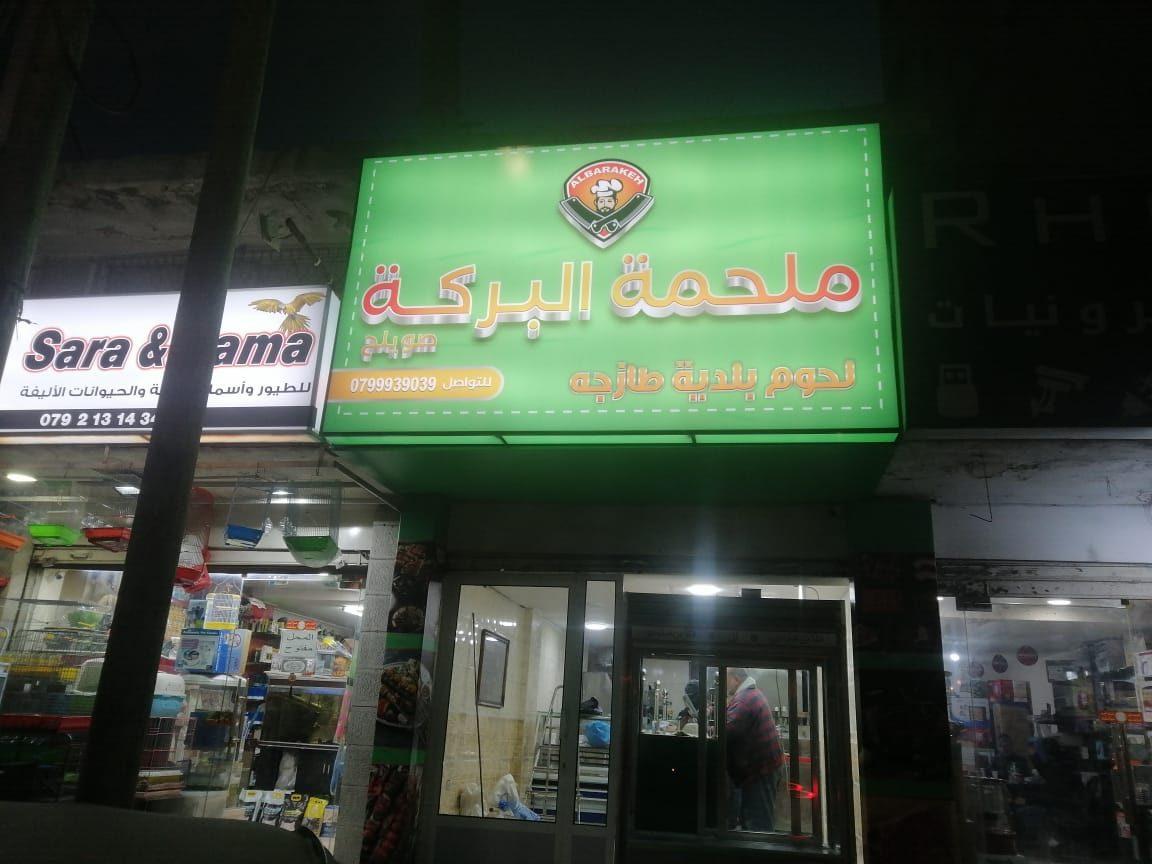 Lit green fascia at night above the storefront