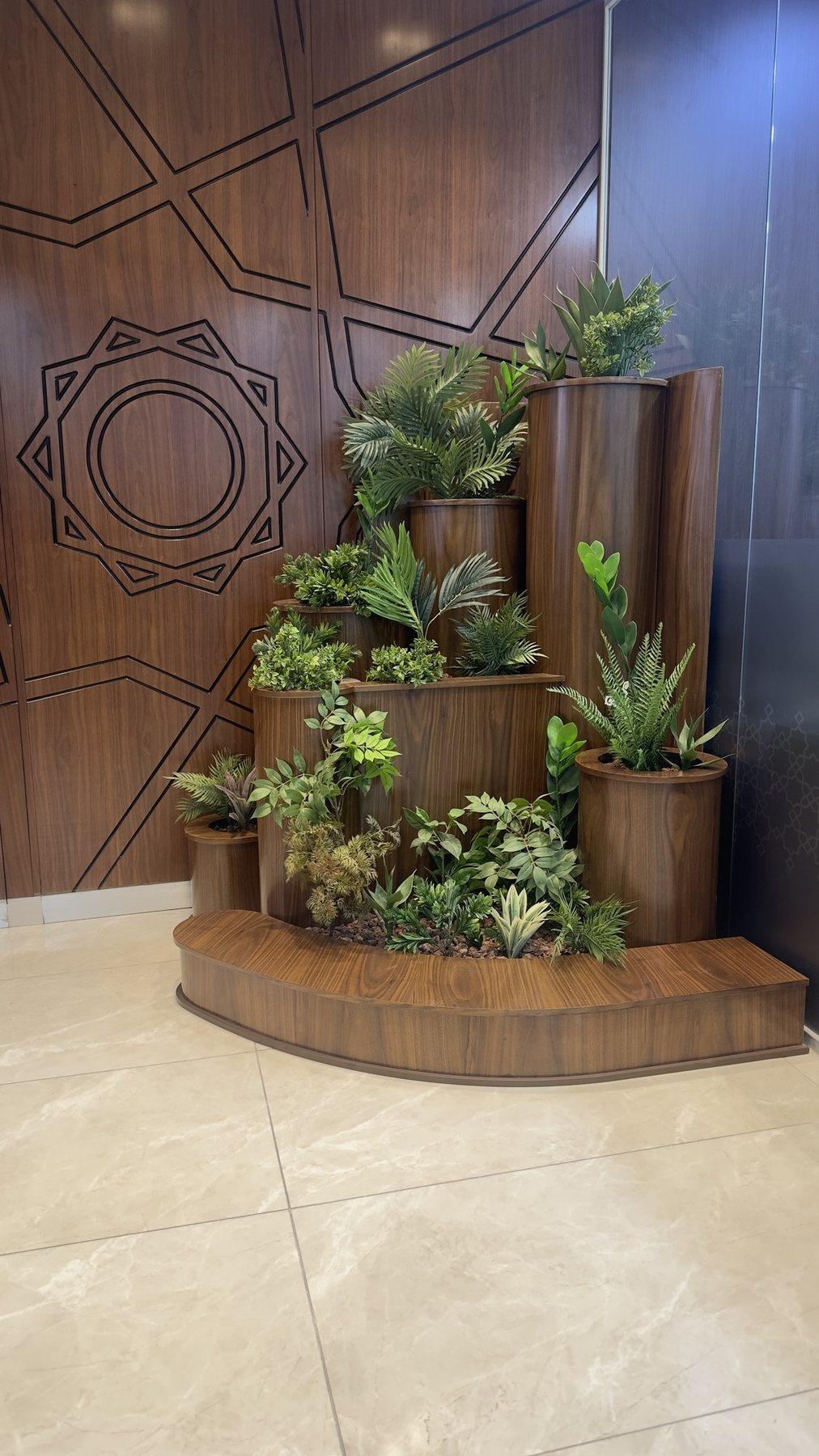 Wood-panelled feature wall with tiered planters and succulents on a curved base.