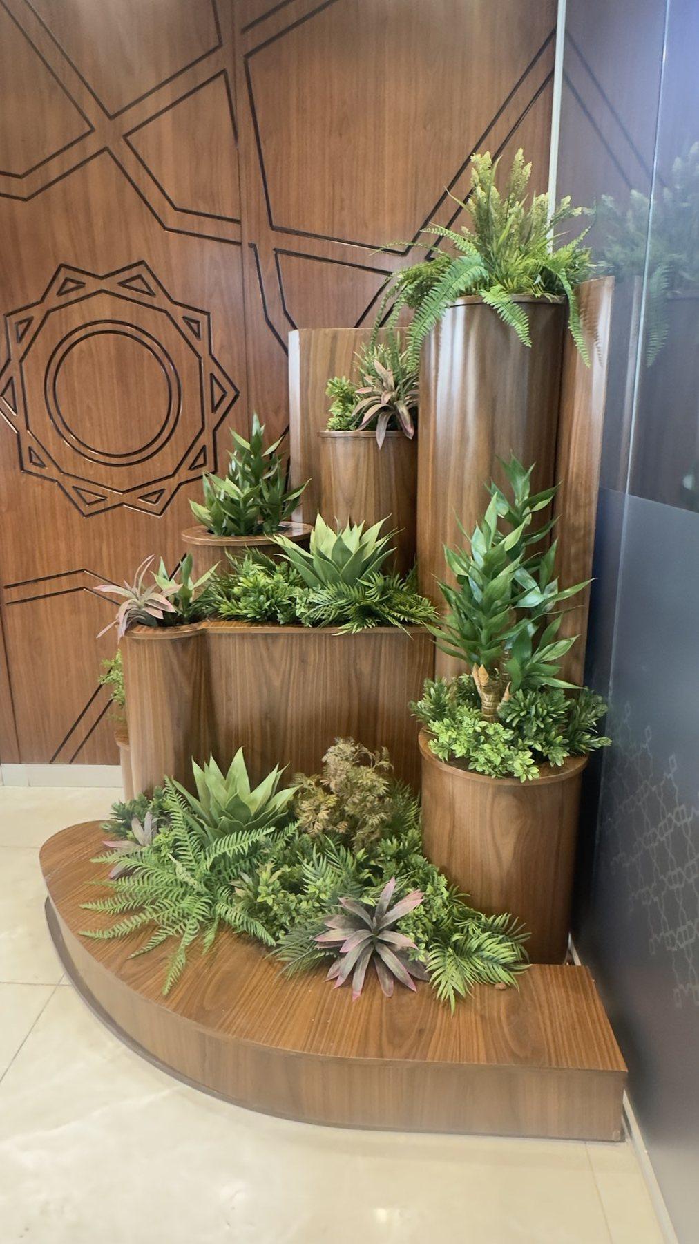Wood planter feature with succulents set into a curved base beside a patterned wall.