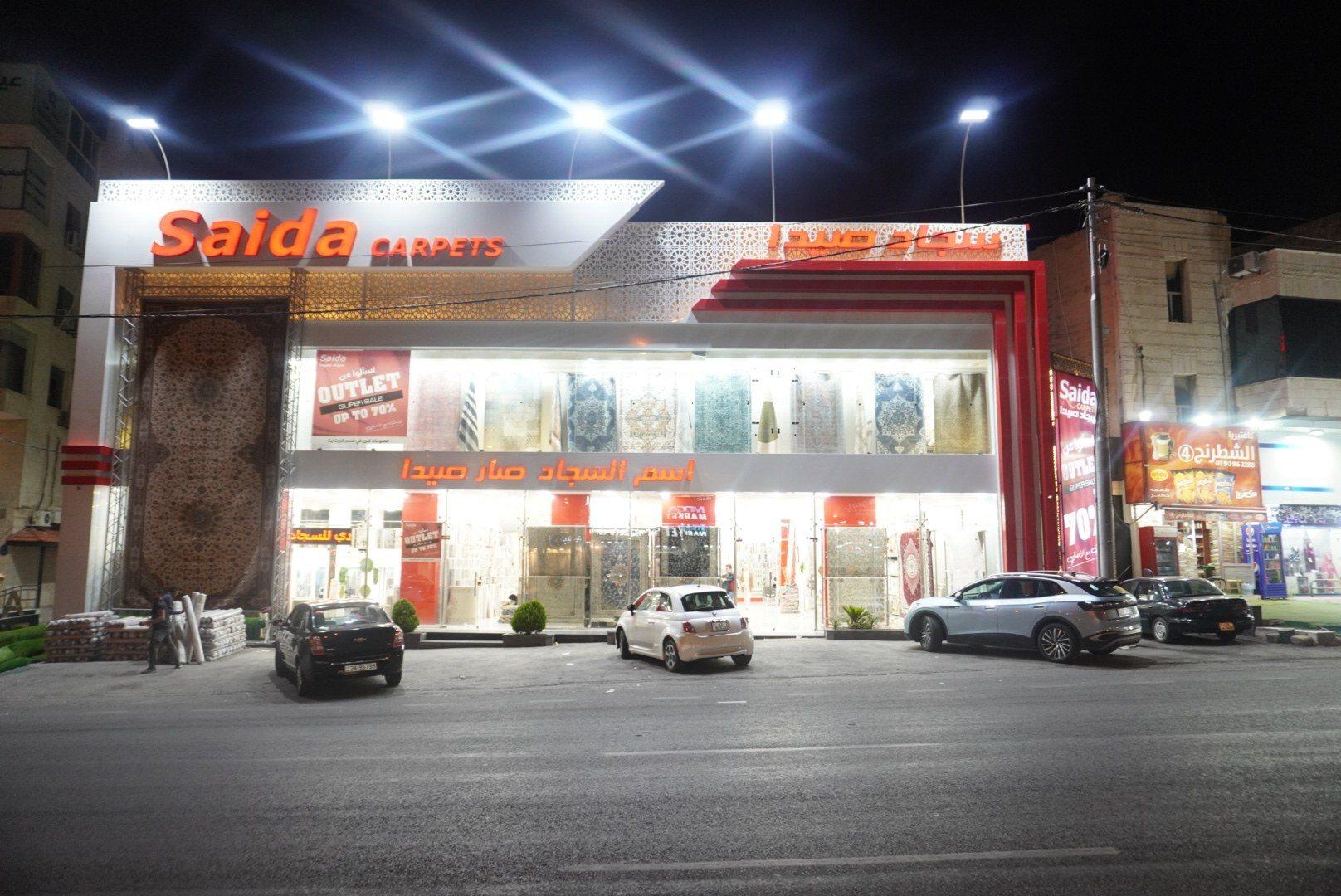 The front of a carpet showroom with an illuminated fascia sign at night.