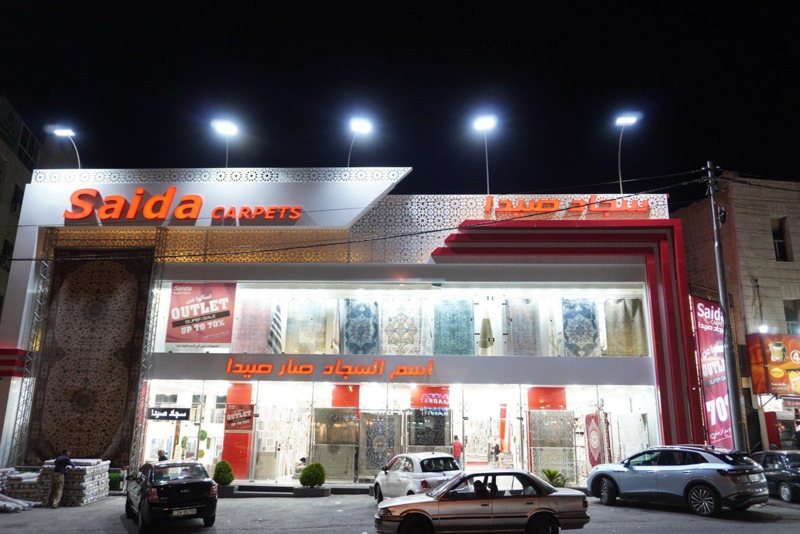 The front of a carpet showroom with an illuminated fascia sign at night.