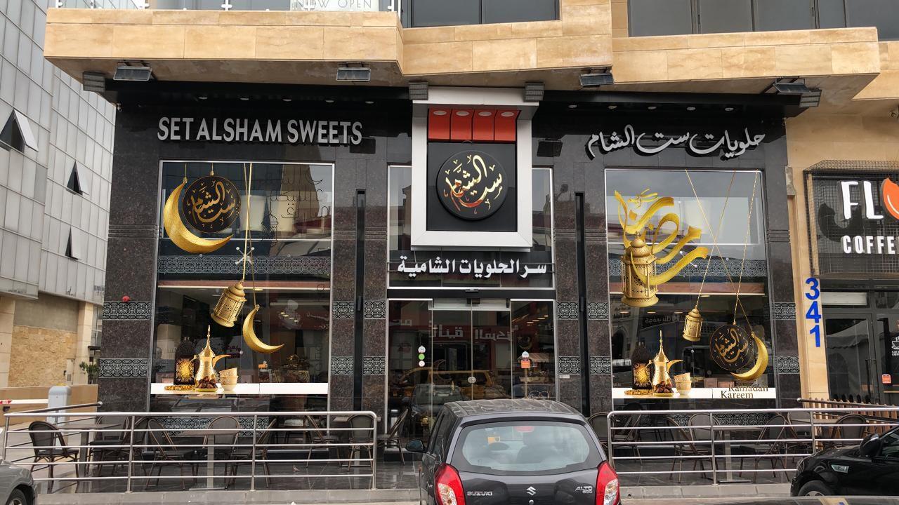 Daytime street view of the black shopfront fascia with gold logo above the windows